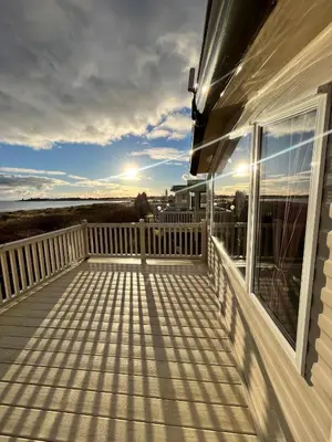 a balcony with a view of the water at Marianne Bay - Southerness Caravan Park with Sea View - Pet Friendly in Mainsriddle